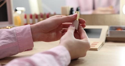 Frau mit Lippenstift und anderen verschiedenen Make-up-Produkten auf Holztisch, Nahaufnahme
