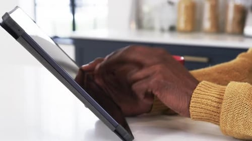 Using tablet at home, man in cozy sweater browsing with coffee nearby