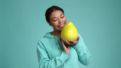 Closeup View of a Cheerful Young Girl Smelling Yellow Pomelo