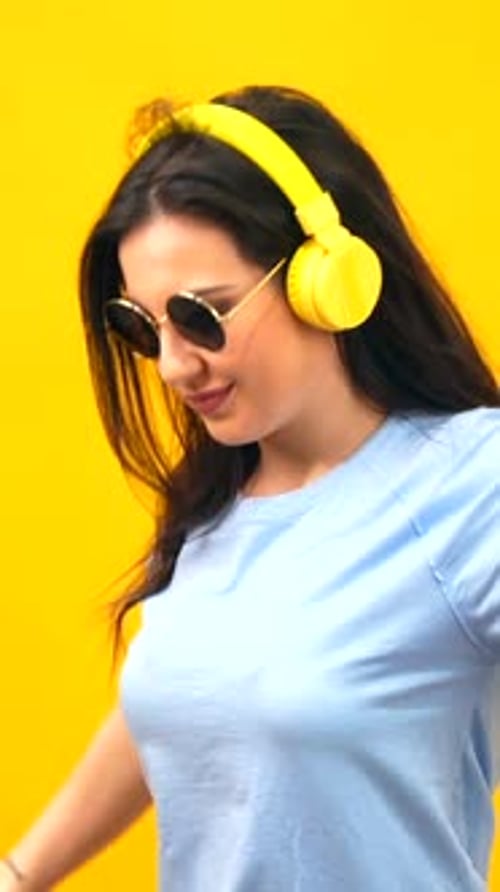Happy woman dancing wearing sunglasses and headphones on the neck