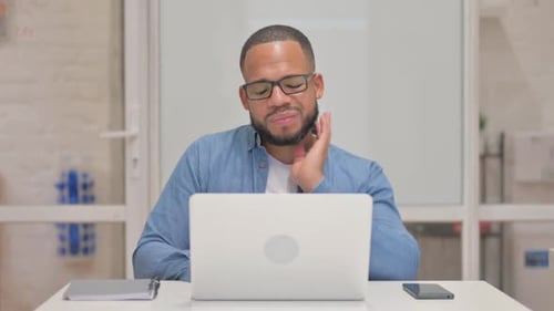 Man Massages Stiff Neck While Working at Laptop