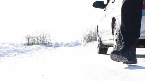 Man setting up warning triangle near broken car on roadside at snowy winter, closeup