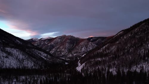 Sunset drone view of storm clouds over a mountain peak during golden hour.