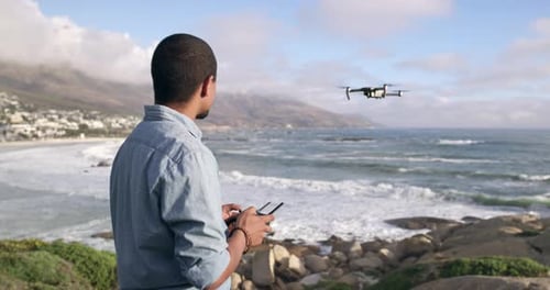 4k video footage of a young man flying a drone at the beach