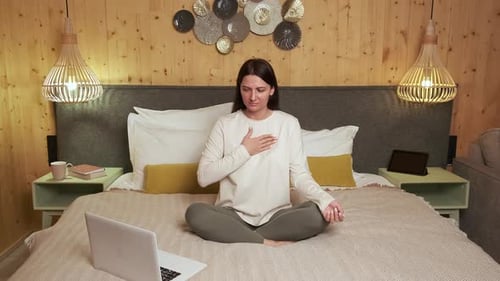 Woman Practicing Online Meditation in Cozy Bedroom
