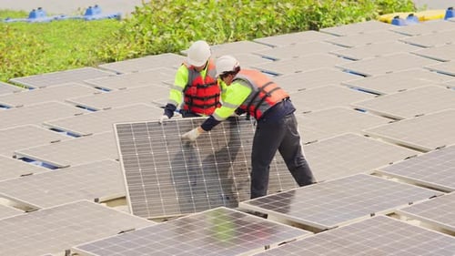 Deux techniciens professionnels se tiennent debout et tiennent un panneau de cellules solaires dans la zone du réseau de base