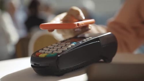 Young Woman Using Smartphone Cashless Wallet NFC Technology to Pay for Order on Bank Terminal in the