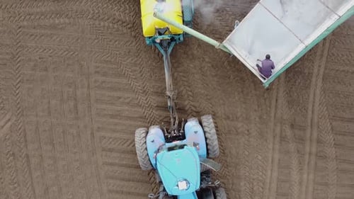 Blauer Traktor mit gelber Sämaschine arbeitet auf dem Feld in der Ukraine OA