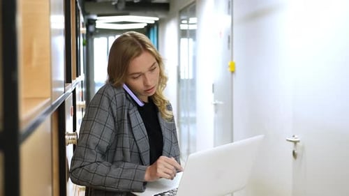 Woman Talks on Phone While Working on Laptop