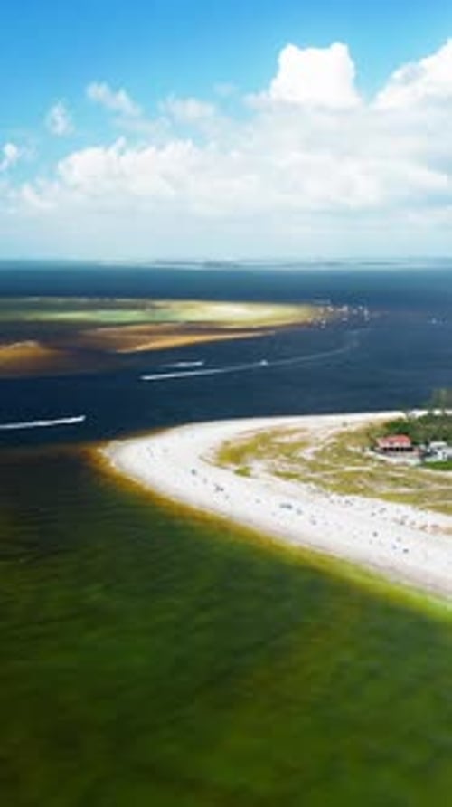 Curved sandy shoreline with boats near shallow ocean sandbars