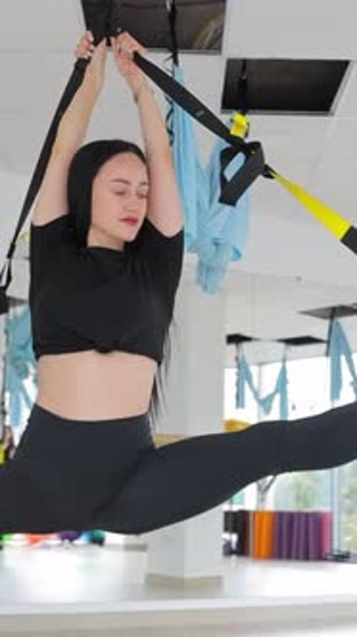 Woman Stretching with Yoga Straps in Fitness Studio