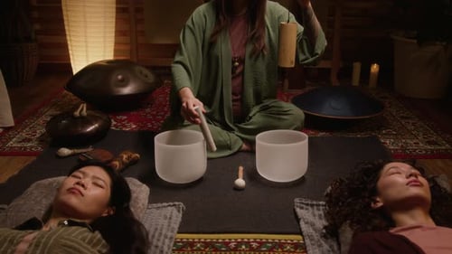 Female Esoteric Practitioner Playing Singing Bowls and Wind Chime in Studio