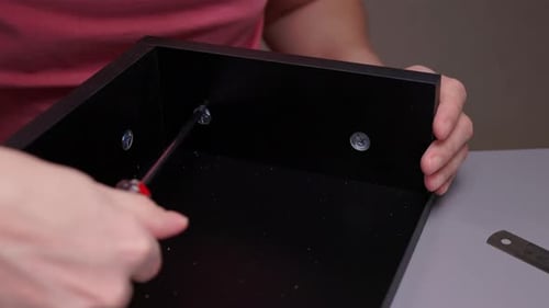 Assembling Furniture with Screwdriver Tightening Screws in Wood