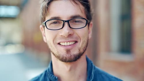 Man Smiling, Wearing Glasses in Urban Environment
