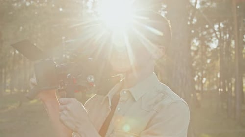 Young Man Filming in Forest with Professional Camera