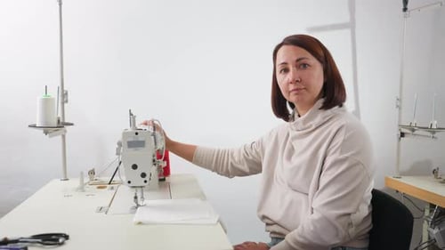 Woman Sewing on a Machine in Bright Workshop