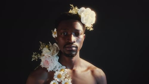 Young Man with Floral Arrangement Posing Against Black