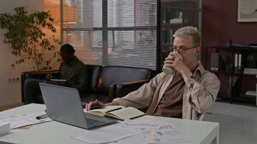 Gen Z Guy Sipping Coffee and Working on Laptop