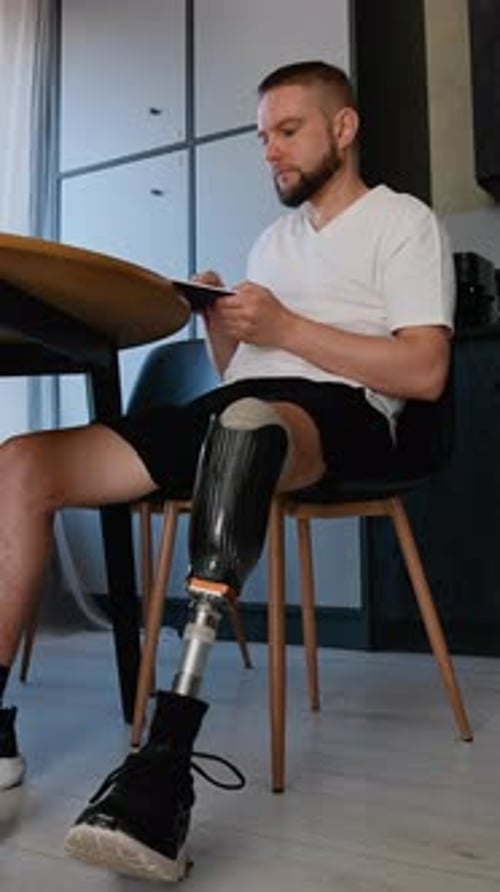 A Man with Prosthetic Leg Reading a Book During Rehabilitation