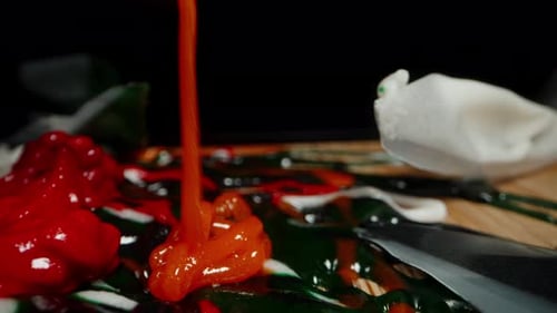 Red icing is squeezed from the bag onto other colors to mix. Sweet preparation. Dolly slider.