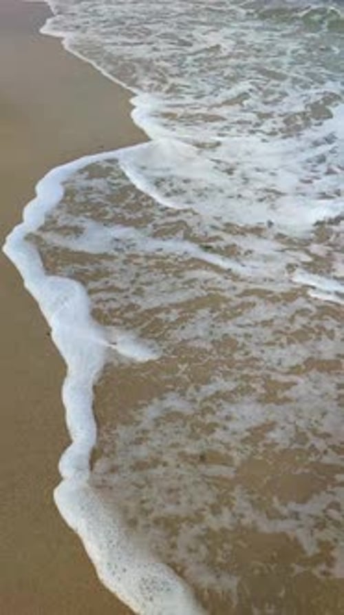 Sea Waves with White Foam Roll on the Sandy Beach of the Seashore Closeup