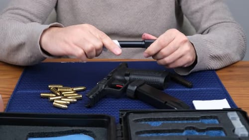 Person Cleaning a Disassembled Black Pistol