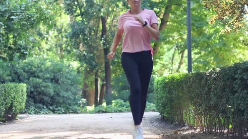 Young woman suffering calf cramp while jogging in the park