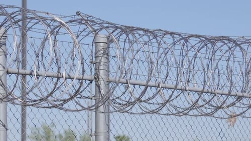 Slow pan across a barbwire fence outside an american jail