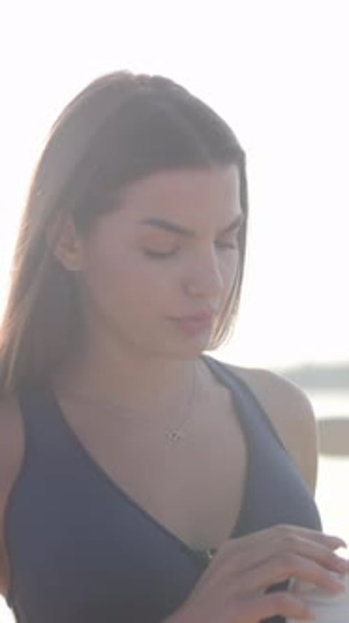 Morning By Coast with Hydration Break Calm Young Woman in Navy Active Wear Rehydrates By Seaside