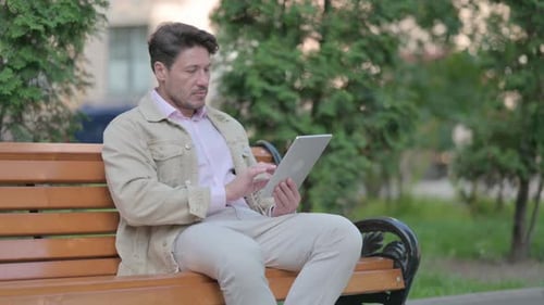 Man Using Tablet on a Park Bench