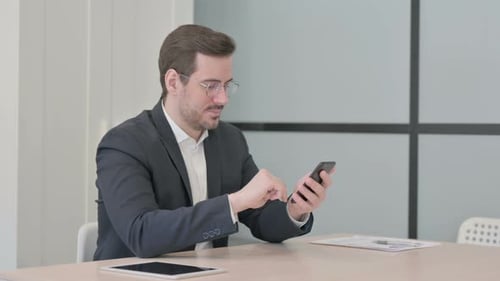 Businessman Browsing Internet on Smartphone in Office
