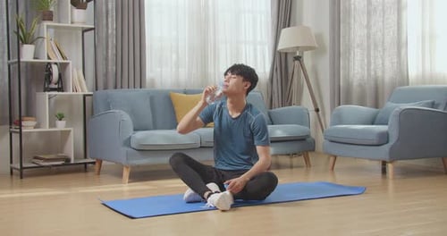 Young Adult Drinking Water after Exercise on Mat
