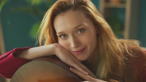 Woman Resting with Guitar Indoors in Natural Light