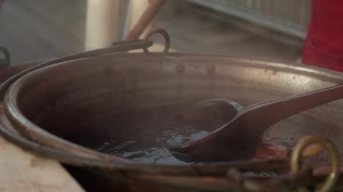 Steam rising from a large pot of mulled wine, being stirred with a wooden spoon. Bath Christmas mark