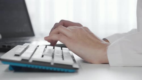 Hands Typing on Computer Keyboard at Office Desk