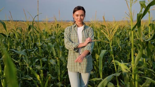 Young Woman Stands Confidently in a Lush Cornfield