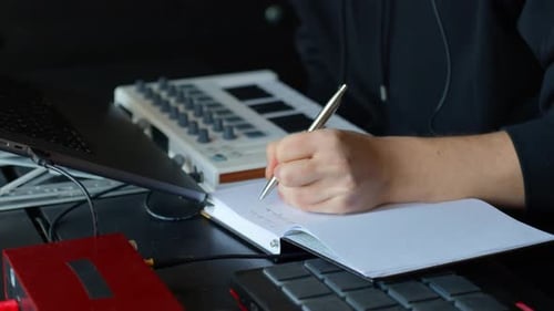 Person Writing in Notebook in Home Recording Studio