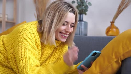 Smiling Woman Using Smartphone Relaxing on Couch