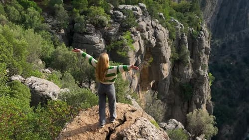Aerial Around Girl Model Stands on Top of Cliff at Mountain Edge Around an Incredible Alpine