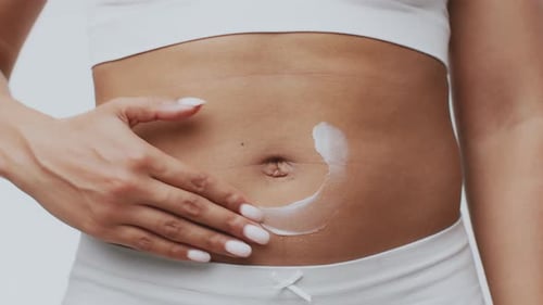 Junge Frau, die zu Hause ein Hautpflegeprodukt aufträgt, um sich selbst zu verwöhnen