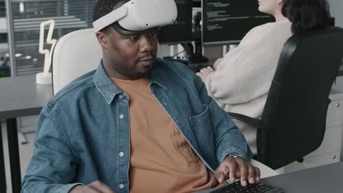 Black Male Program Developer in VR Glasses Using Computer in Office