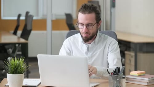 Professional Working on His Laptop in a Modern Office