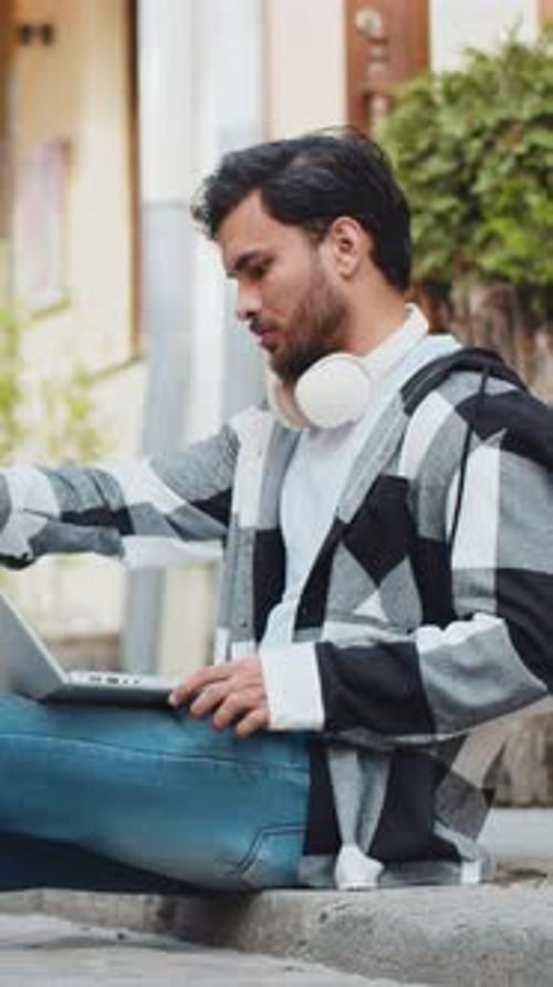 Indian Man Freelancer Sitting on Street Closes Laptop Screen Finishing Work Smiling in City Outdoors