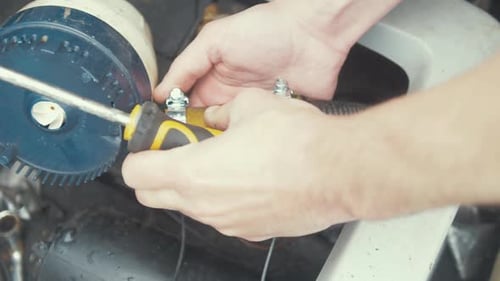 Hands Tighten Hose Clamps on Machinery