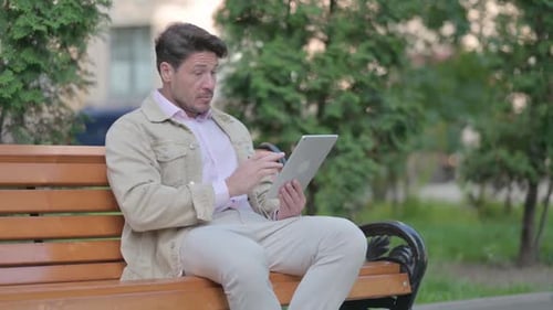 Adult Man Using Tablet on Park Bench