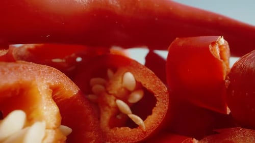 Sliced red pepper, one whole pepper at the top. Dolly slider extreme close-up.