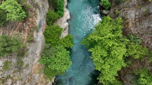 Aerial View of a Turquoise River Flowing Between Rocky Cliffs and Lush Green Foliage