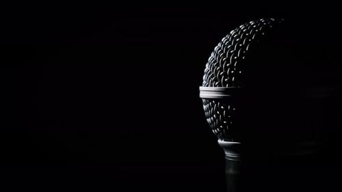 Das Vocal-Handmikrofon dreht sich langsam bei Hintergrundbeleuchtung auf schwarzem Hintergrund