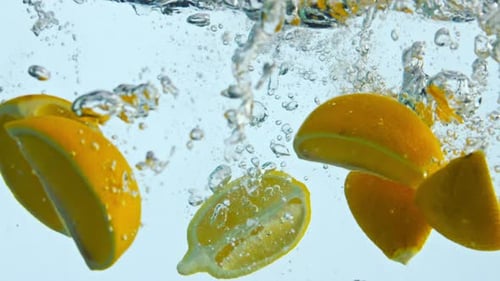 Lemon Slices Falling Into Water With Bubbles