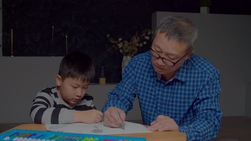 Hübscher asiatischer Großvater und Enkel genießen es, zu Hause zusammen zu zeichnen